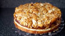 A delicious almond-topped cake on a dark surface.