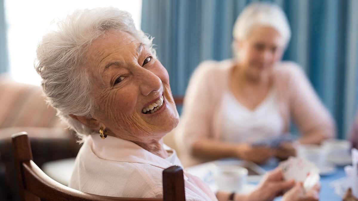 Two elderly women enjoying a cheerful moment together indoors.