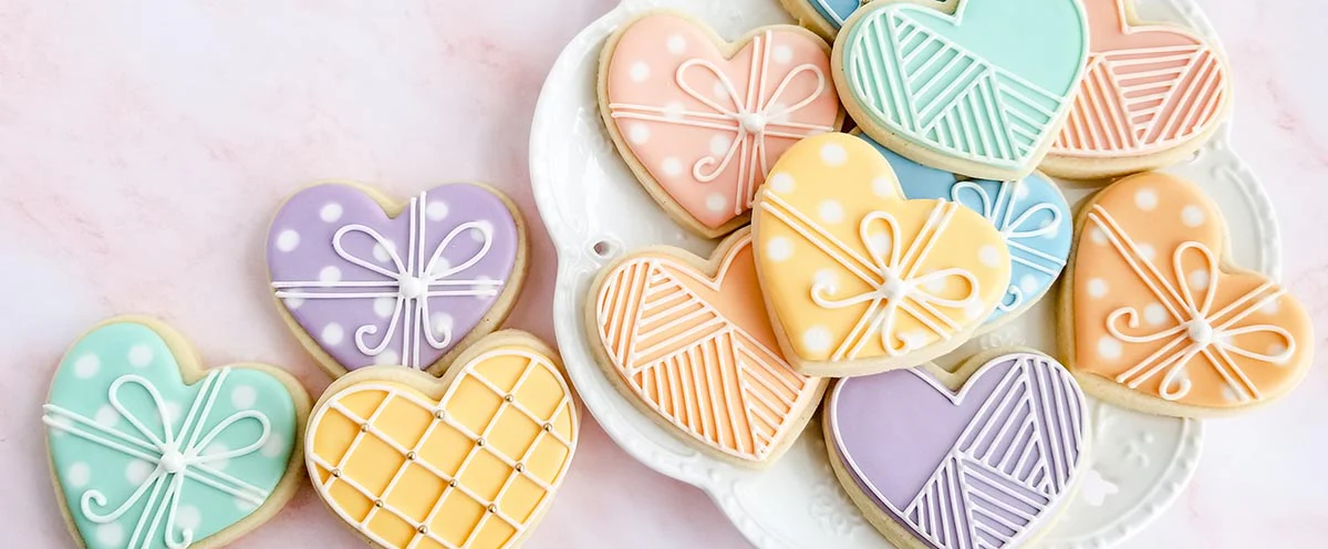 Colorful heart-shaped cookies with intricate icing designs on a white plate.