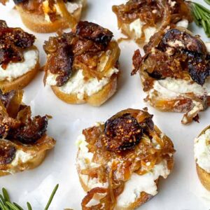 Appetizers with creamy cheese, caramelized onions, and nuts on sliced bread.