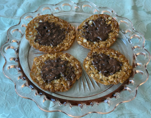 Four oatmeal cookies with chocolate chunks on a glass plate.