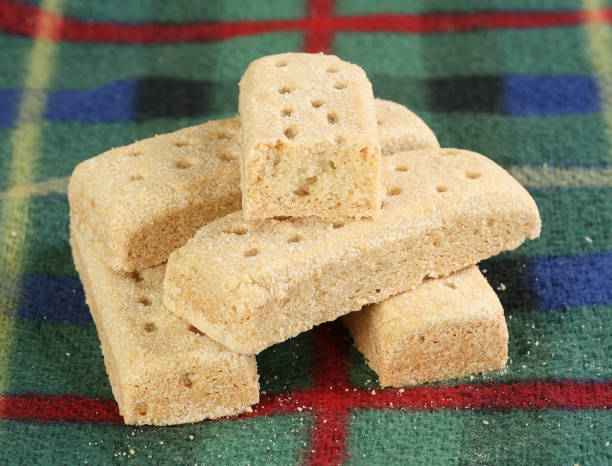 Traditional shortbread cookies stacked on a plaid cloth.