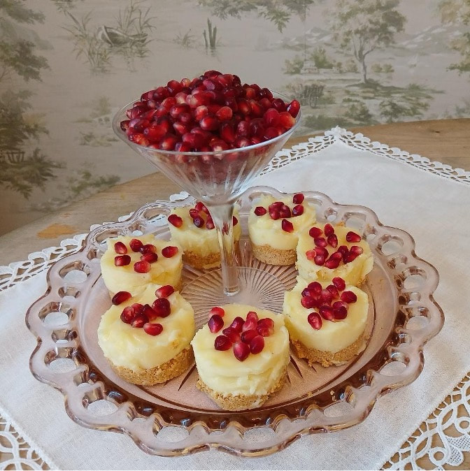 Mini cheesecakes topped with red berries on a decorative glass plate.