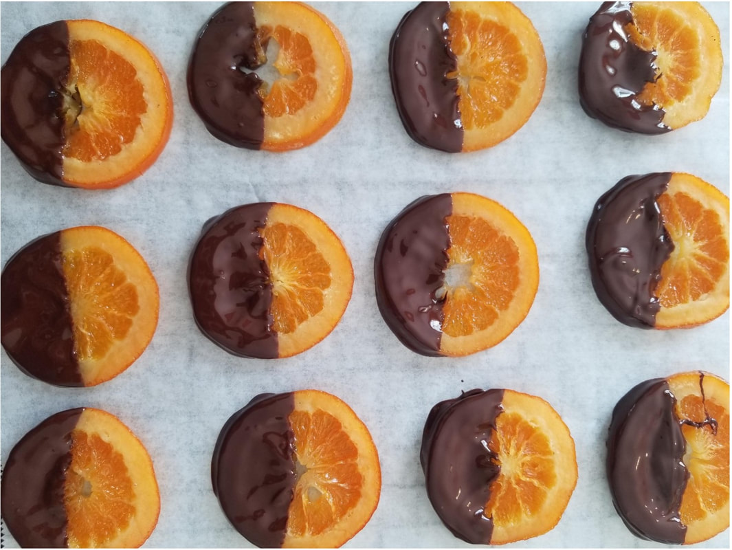 Chocolate-dipped orange slices arranged neatly on parchment paper.