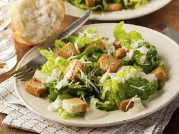 Fresh Caesar salad with croutons and grated cheese on a white plate.