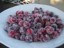A bowl of frosted red berries covered in ice crystals.