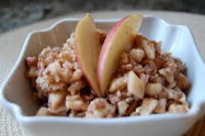 Bowl of oatmeal topped with apple slices.