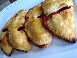 Three golden-brown fried empanadas on a white plate.
