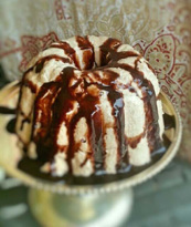 Bundt cake drizzled with chocolate glaze on a decorative plate.