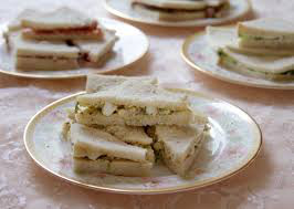 Plate of small, crustless tea sandwiches stacked neatly.