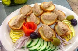 Appetizer platter with crostini and pâté, garnished with fresh vegetables.