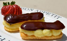 Two chocolate-covered éclairs with cream filling on a plate.