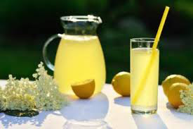 Refreshing lemonade in a glass pitcher and a tall glass with lemons.
