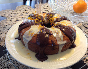 A bundt cake drizzled with chocolate and white icing on a plate.