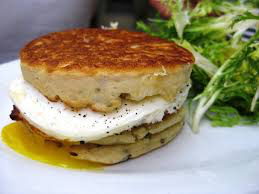 Stack of savory potato pancakes with a dollop of sour cream and fresh salad.