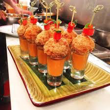 Gourmet appetizers served in shot glasses with crispy toppings and garnishes.