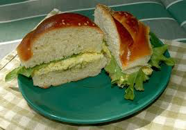 A sandwich with egg salad and lettuce on a bun.