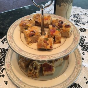 Two-tier plate stand with homemade fruitcake slices and a cup of tea.