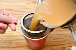 Pouring tea through a strainer into a cup.