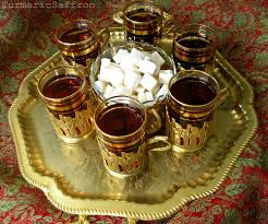 Traditional tea set with six glasses and sugar cubes on a brass tray.