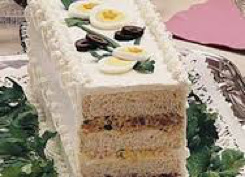 Sliced layered cake with cream and fruit toppings.