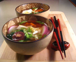 A bowl of colorful vegetable soup with chopsticks beside it.