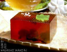 A square red gelatin dessert with a green leaf decoration on top.