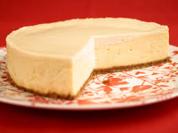A creamy cheesecake with a slice removed on a decorative plate.