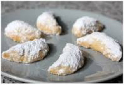 Powdered sugar-coated crescent cookies on a plate.