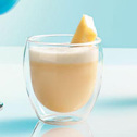 A creamy beverage with a lemon twist in a double-walled glass.