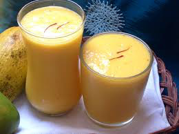 Two glasses filled with creamy mango lassi topped with saffron strands.
