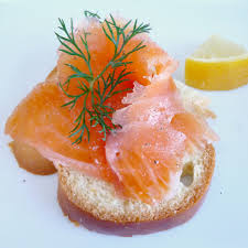 Smoked salmon on a slice of bread garnished with dill and lemon.