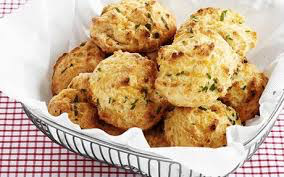 Basket of freshly baked cheese biscuits with herbs.
