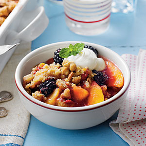A bowl of fruit crisp topped with whipped cream and mint.