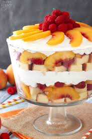 A layered peach and berry trifle dessert with whipped cream.