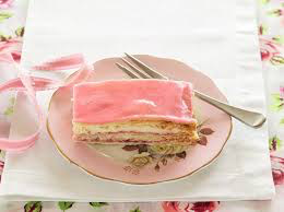 A slice of layered dessert with pink icing on a floral plate.