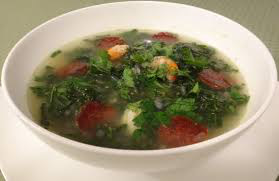Bowl of leafy green soup with tomatoes and herbs.