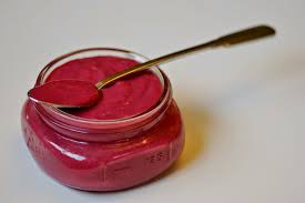 A jar of vibrant pink beetroot hummus with a spoon.