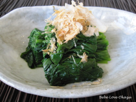 A plate of cooked spinach topped with bonito flakes.