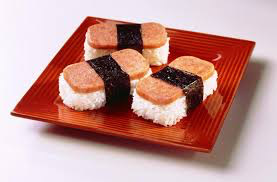 Four pieces of musubi with Spam on a wooden plate.