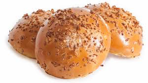 Close-up of three bread rolls topped with flax seeds on a white background.