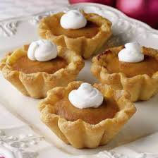 Mini pumpkin pies topped with whipped cream on a plate.