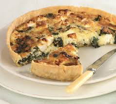A slice of spinach and cheese quiche on a plate with a knife.