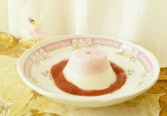 A delicate pink dessert with red sauce on a decorative plate.