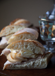 Close-up of sandwiches with sliced meat and cheese on crusty bread rolls.