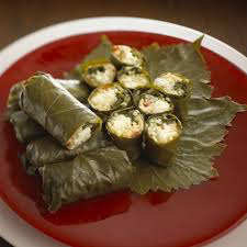 Traditional stuffed grape leaves served on a red plate.
