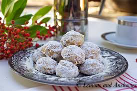 Plate of powdered sugar-coated cookies with red berries in the background.