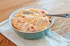 A bowl of creamy pimento cheese spread with a spoon.