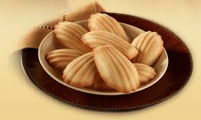 Plate of madeleine cookies on a brown dish.