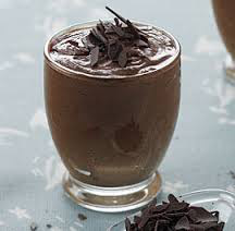 A glass of chocolate mousse topped with chocolate shavings.